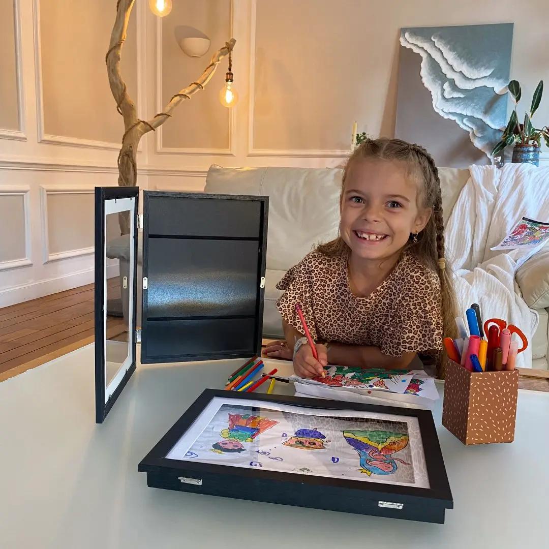 Enfant utilisant un cadre dessin pour exposer ses créations artistiques
