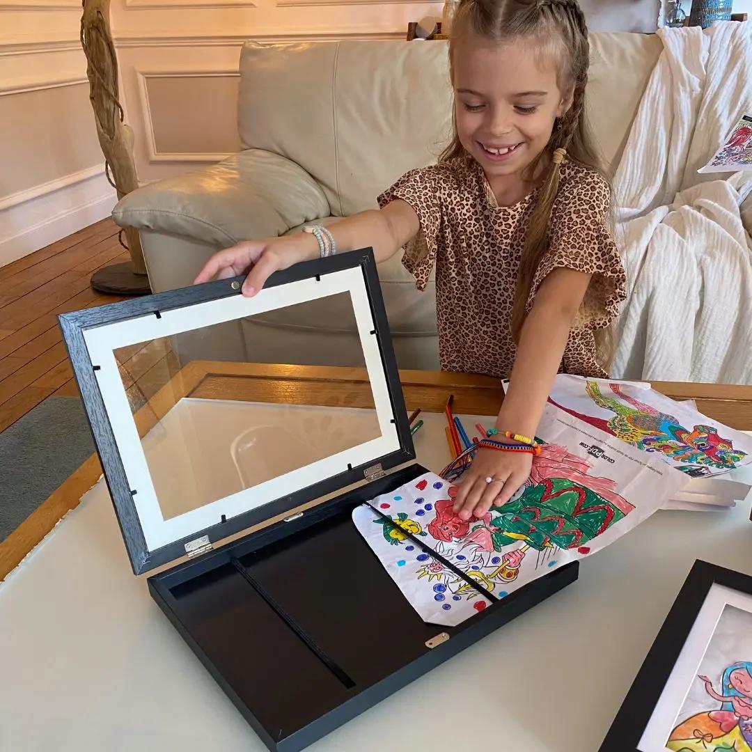 Enfant utilisant facilement un cadre pour ranger ses dessins