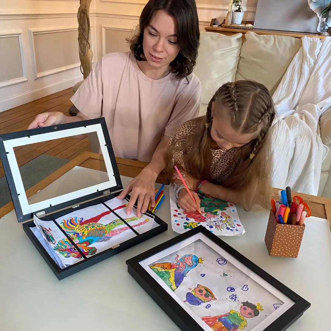 Maman et enfant utilisant un cadre pour ranger et exposer des dessins