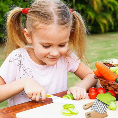 Enfant utilisant un couteau sécurisé du kit cuisine enfant pour couper des légumes en autonomie