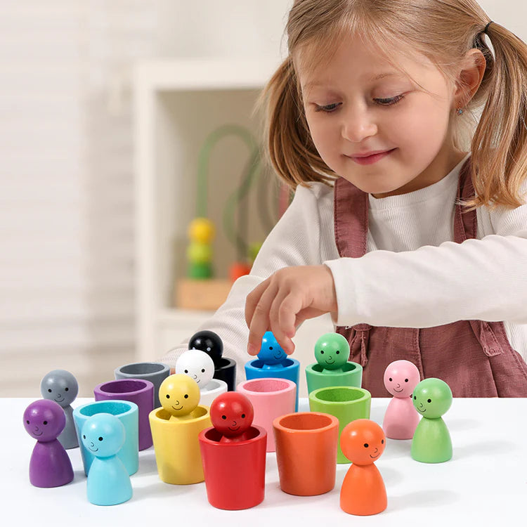 Enfant de 3 ans jouant avec des tasses Montessori en bois colorées pour développer la motricité fine